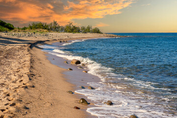 stone and sand beach at sunset on island corsica