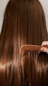 Red hair being combed with a wooden comb in slow motion. Texture of ginger female hair close-up.
