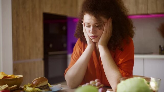 Pensive young woman eating grape instead of junk food, self-control and diet