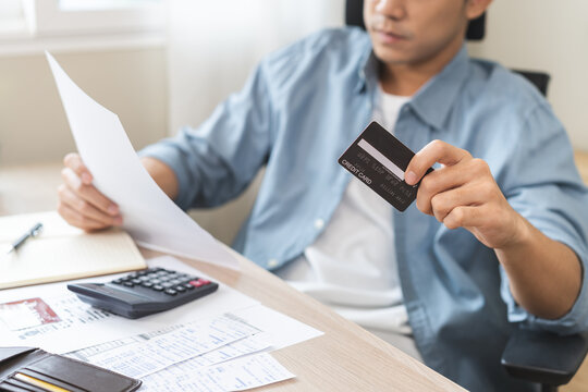 Bad financial concept, frustrated asian young man having debt, reading paper report from bank, stress calculate expense from credit card invoice or bill no money to pay, mortgage or loan, bankruptcy.