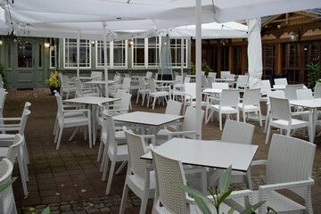 Modern outdoor restaurant terrace with white wicker furniture and sun umbrellas in Sopot, Poland