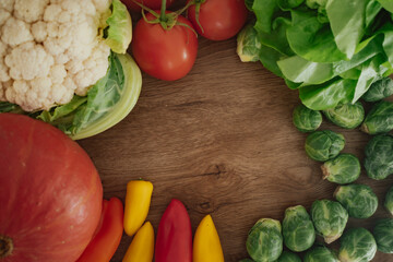 Colorful assortment of fresh vegetables arranged in a border on a rustic wood background