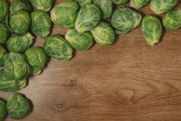 Fresh, raw brussel sprouts scattered on a rustic wooden table with copy space.