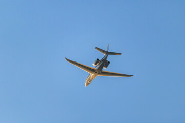 Private jet aircraft flying overhead in blue sky