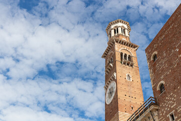Fototapeta premium The Torre dei Lamberti, Clock Verona tower on blue sky background, popular tourist destination of Europe, stands proudly in the historic city center, offering panoramic views