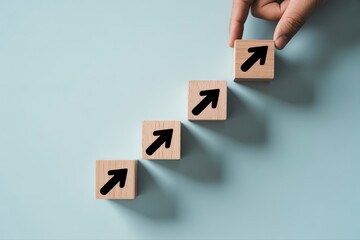 Hand placing wood block with arrow up on stack of blocks on blue surface