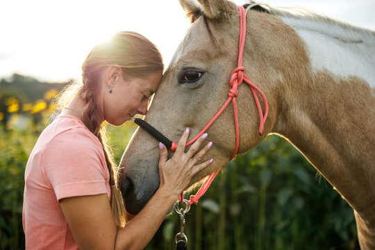 Smiling woman bonding with her horse, showing trust, emotional connection and friendship between people and animal