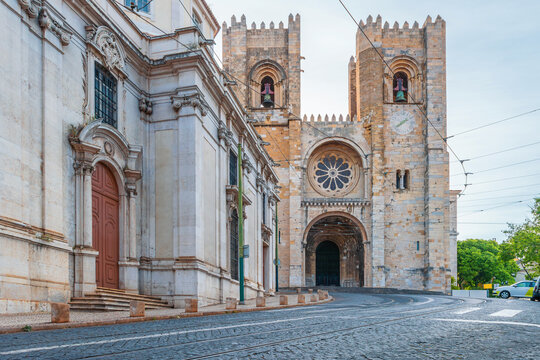 Front view of Lisbon Cathedral with tram tracks and cobblestone street in Lisbon city, Portugal. Gothic architecture in Alfama district of old town of Lisboa. Travel and tourism in Europe