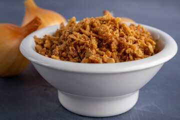 fried onions in a bowl on a gray background
