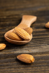 yellow brown nuts of unroasted almonds with a wooden spoon on the table, a large number of hard raw almonds on the table during cooking