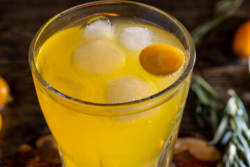 citrus-flavored orange juice and fresh kumquat fruits on a wooden table, delicious and fresh orange juice and fresh kumquat next to a glass
