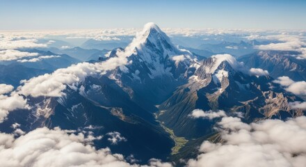 Naklejka premium Majestic snow-capped mountain peak pierces through soft clouds, revealing a lush green valley below, inspiring awe and adventure.