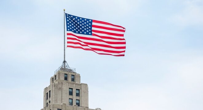American flag waving proudly atop a historic building against a clear blue sky, symbolizing patriotism and national pride - Powered by Adobe