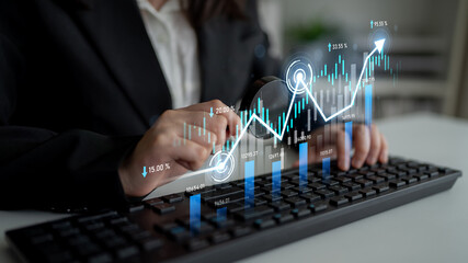 A business professional examines financial data on a keyboard, accompanied by digital graphs that...