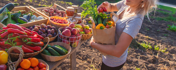 A woman buys fruits and vegetables at a farmers market. Selective focus.