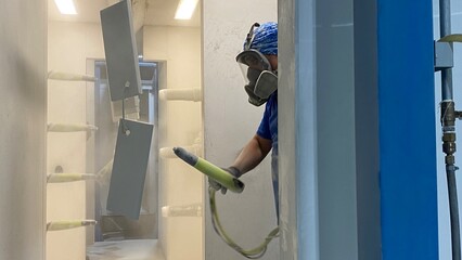 Painting iron cans inside a factory using powder coating