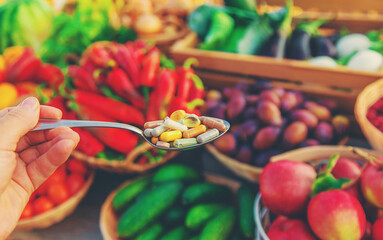 Vitamins and supplements in a spoon with vegetables. Selective focus.