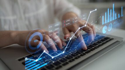 A professional engages in financial data analysis using a laptop, with digital graphs illustrating...