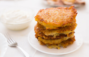 Potato pancakes with sour cream on white plate