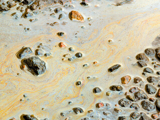Stains of gasoline and oil in a puddle on contaminated ground