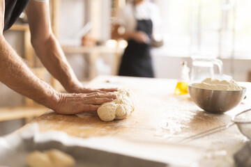 Baker's hands kneading raw dough in bakery