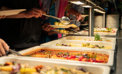 Hotel guests serve food on plates from the buffet in the hotel restaurant