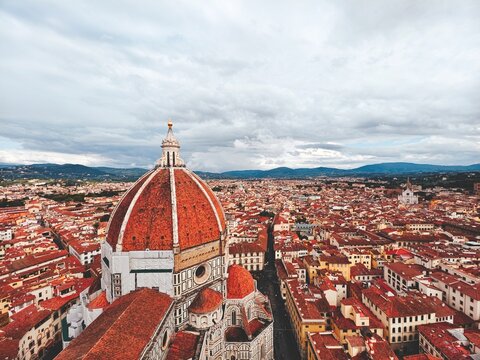 High angle view of Florence city skyline, terracotta dome of Florence Cathedral and many red rooftops under a cloudy sky