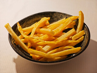 golden, crispy deep-fried french fries in bowl. Close up