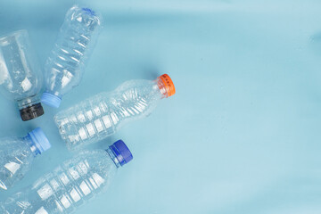 Used plastic bottles scattered on a blue background, symbolizing recycling, waste management, and environmental awareness.