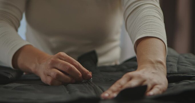 Close up of a woman hands zipping up a black textile jacket Slow motion.