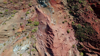 Eroded red rock cliffs with layered slopes drone view. Bright sandstone canyon