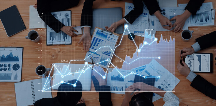 A diverse business team collaborates on data analysis, surrounded by various graphs and charts, revealing insights for strategic decision-making in an office environment. Scalp