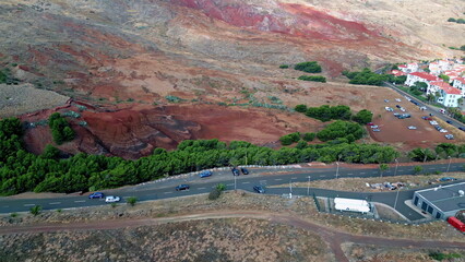 Drone road stretching volcanic red slopes. Highway running to small village