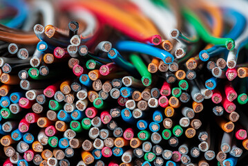 A stack of multicolored copper electrical wires, close-up cross-section view