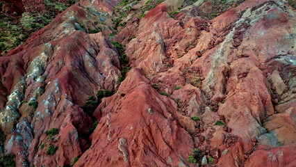 Rocky red cliffs scattered boulders eroded slopes covering highland areas. 