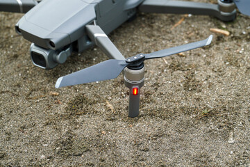 A modern drone rests on sandy ground, offering a glimpse into aerial technology and innovation. Ideal for illustrating themes of adventure, exploration, videography and remote operation.