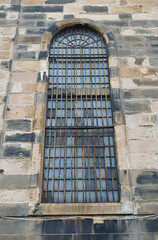 Arched Window with Iron Security Grill in Stone Wall of Old Church 