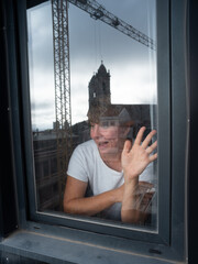 Woman looking out the window and waving her hand as if she saw someone she knows outside