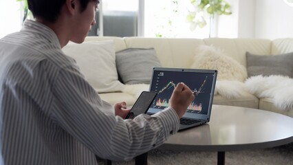 株価の上昇を見て喜ぶアジア人男性