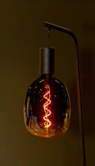 Large light bulb hanging from a ceiling lit in modern interior