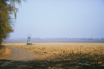 Tractor working dry field during autumn harvest