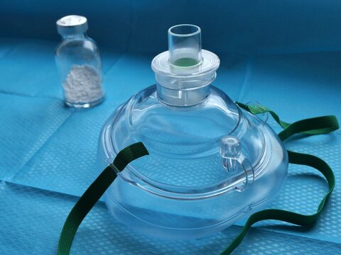 Masque pour pratiquer la r&eacute;animation cardio-pulmonaire, accompagn&eacute; d'un flacon de m&eacute;dicament en poudre sur fond de champ st&eacute;rile