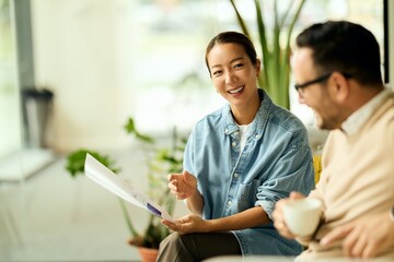 Asian Woman and Colleague Discussing Document in Bright Modern Office Setting