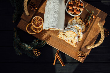 Christmas stollen on a wooden board with green branches of a Christmas tree. Christmas background, Christmas desserts