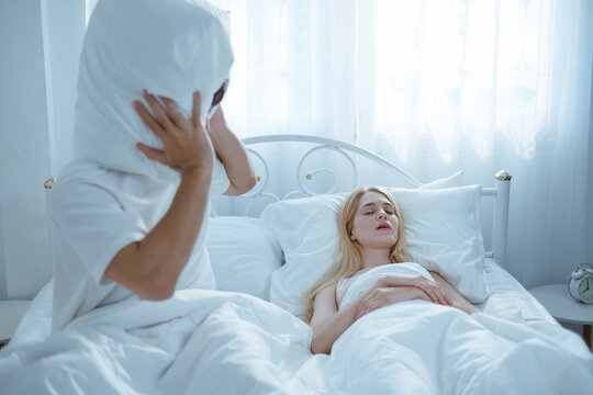 A young man is trying to stop his wife from snoring because she snores very loudly.