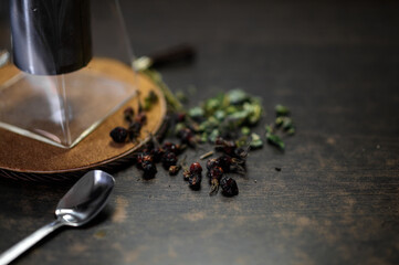 brewing tea in a glass teapot and next to it is a glass mug with herbs and crumbly tea scattered on...