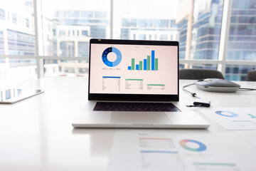 Open laptop on workplace table with analytic diagrams