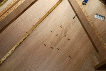 This close-up shot from above depicts the process of assembling furniture from wooden panels, with...