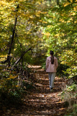 Girl walking forest path during autumn season