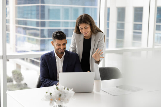Two multiethnic business company colleagues using one laptop